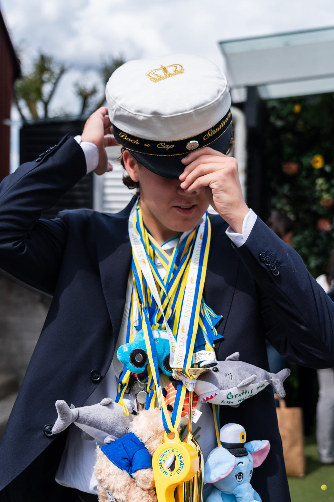 Student tar på sig sin studentmössa från Back a Cap med guldkrona på kullen på studentdagen